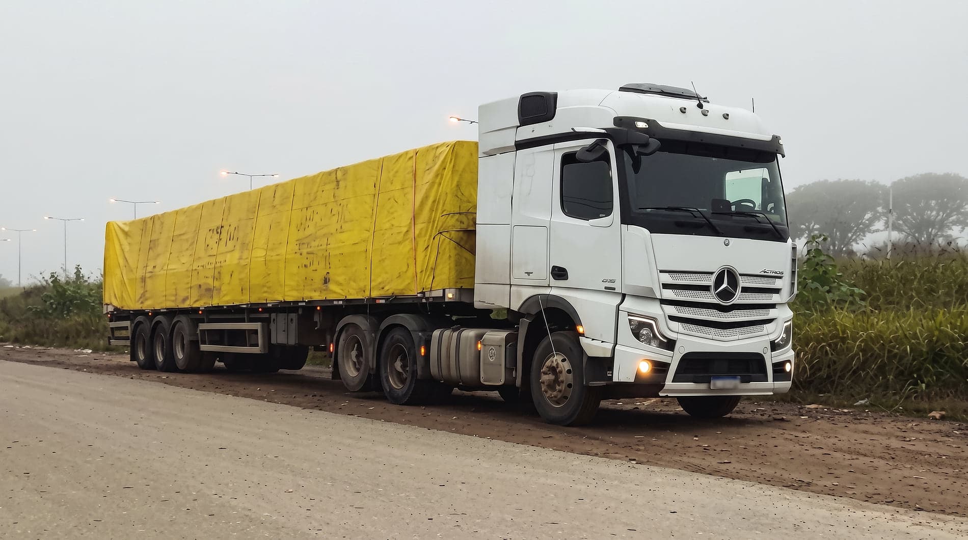 Semirremolque de tres ejes con carga lonada, remolcado por un Mercedes-Benz Actros